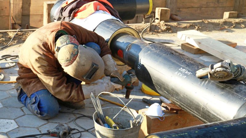 Ein Handwerker arbeitet an einer Fernwärmeleitung.