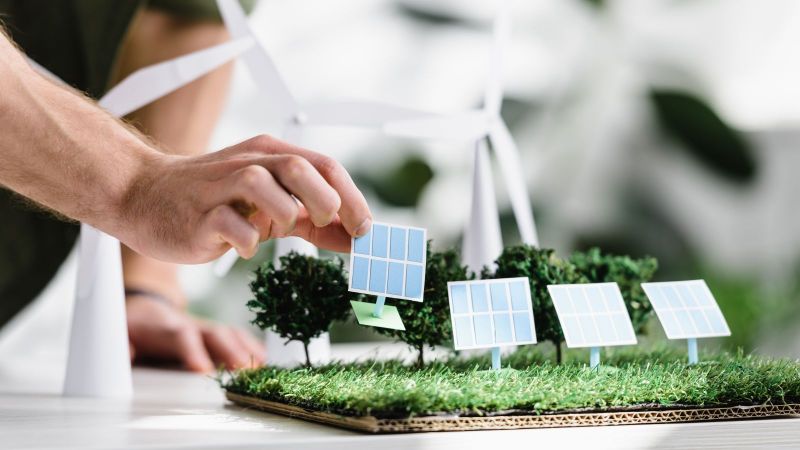 Symbolfoto: Miniaturmodell mit Windkraftanlagen und Solarmodulen aus Papier.