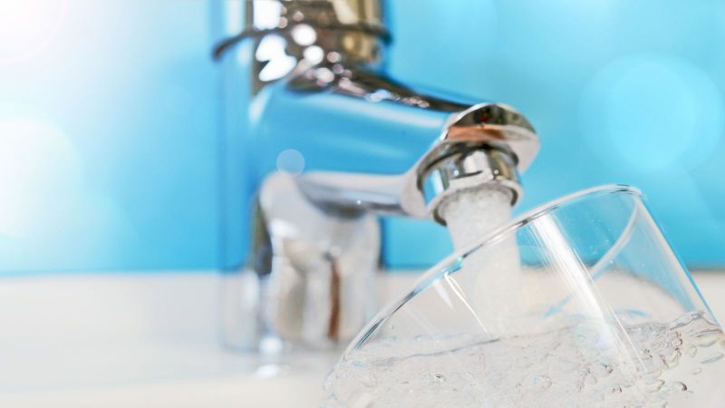 Wasser fließt aus Wasserhahn in Glas