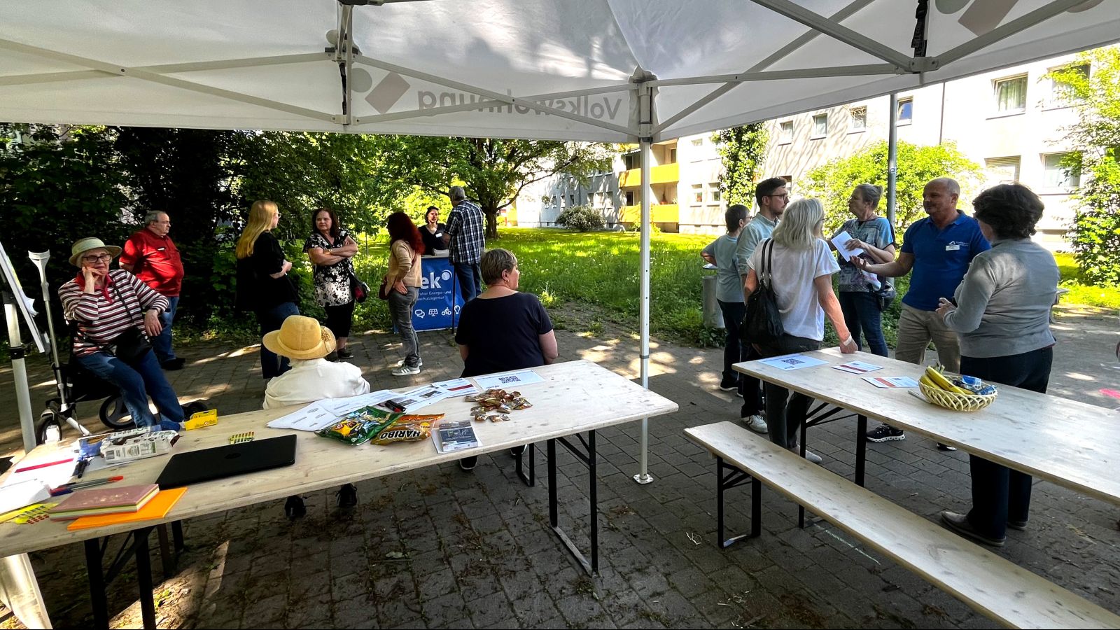 Infostand zwischen den Mehrfamilienhäusern mit einigen Besucherinnen und Besuchern.