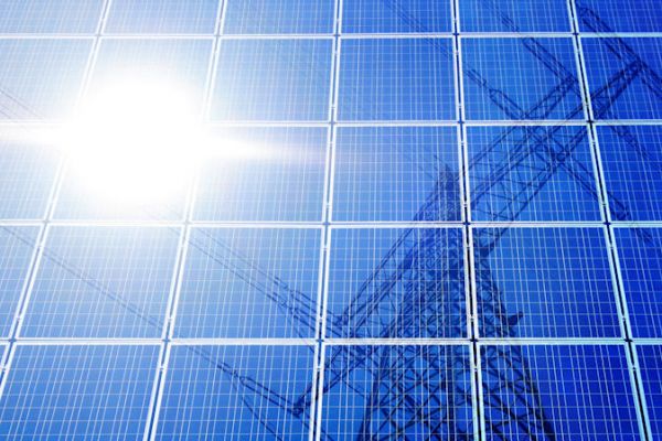 Bild: ©@nt - stock.adobe.com Zu sehen ist, wie sich die Sonne und ein Strommast auf einem Photovoltaik-Modul spiegeln.