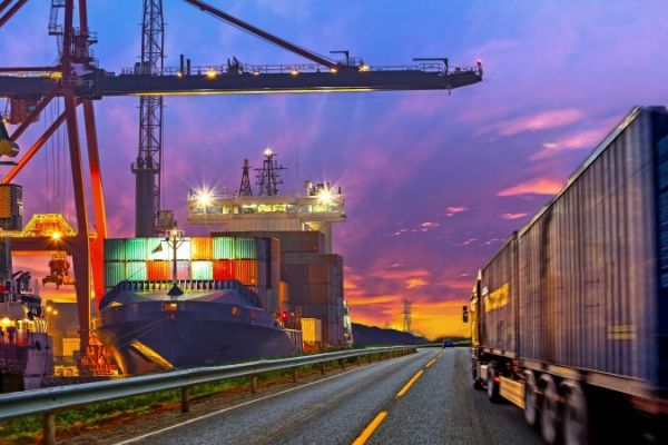 Energiewende in der Industrie Symbolbild Energiewende in der Industrie: LKW fährt in Abenddämmerung an Bausstelle mit Kran vorbei.
