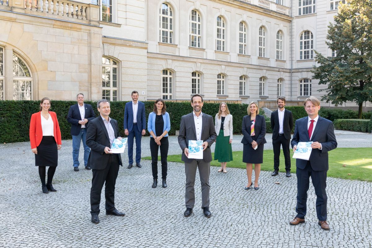 Gruppenfoto im Rahmen der Übergabe der Forschungsagenda, Personen halten Broschüre in der Hand